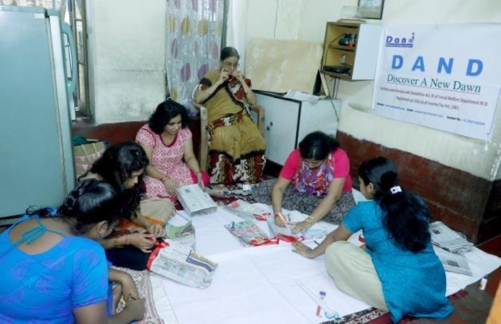 Trainees working on craft materials on the floor of the DAND workshop.